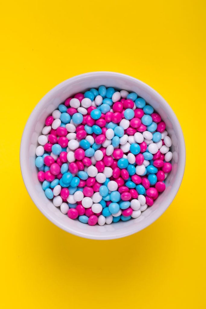 A white bowl filled with colorful candy against a vivid yellow background, perfect for food promotions.
